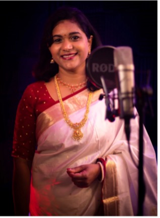A person in a white sari and gold necklace    Description automatically generated